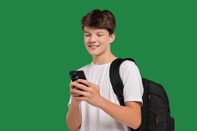 Photo of Teenage boy with smartphone and backpack on green background