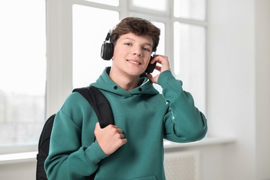 Photo of Teenage boy in headphones with backpack indoors