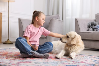 Photo of Girl with her cute Golden Retriever dog on rug at home