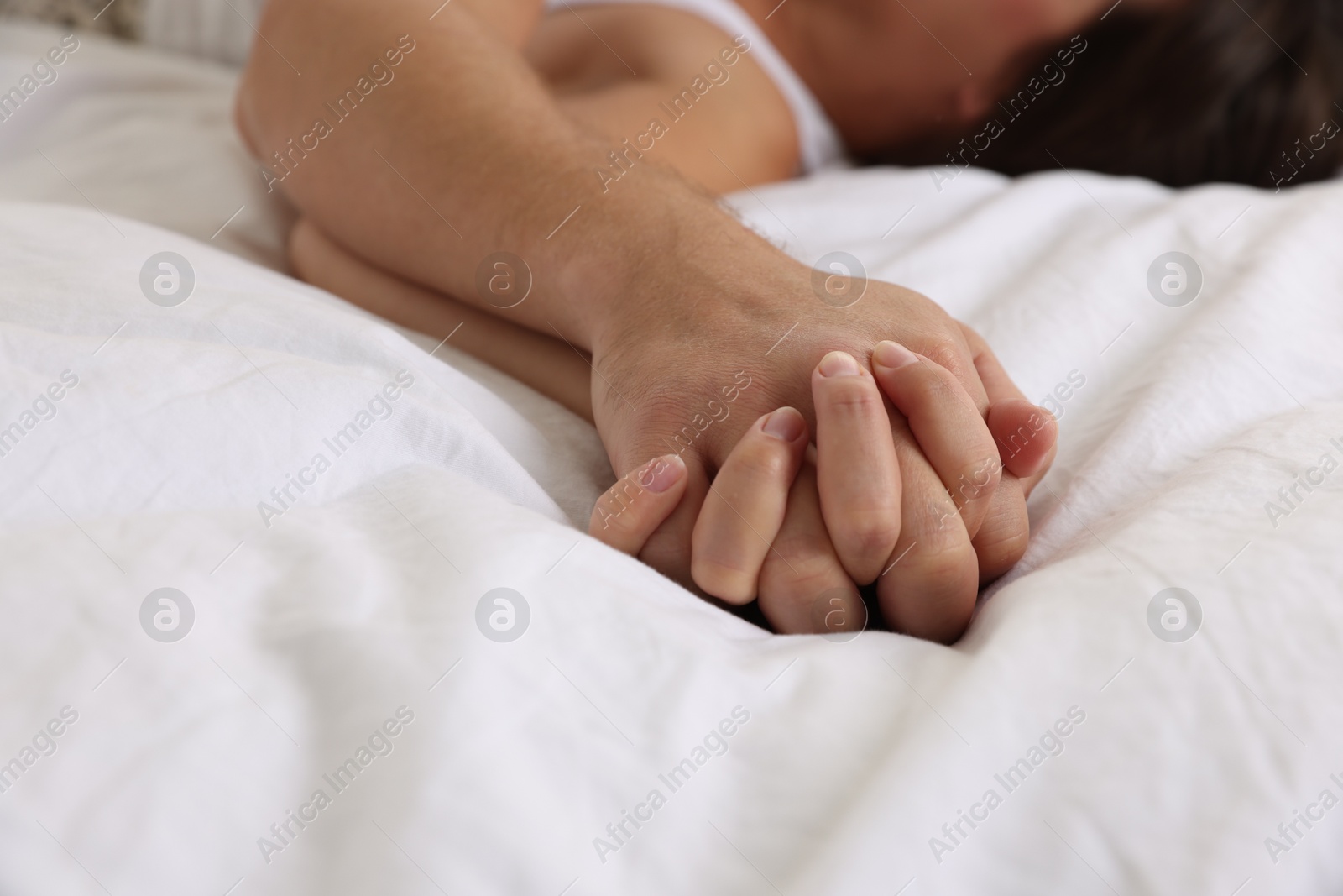 Photo of Lovely couple holding hands in bed, closeup