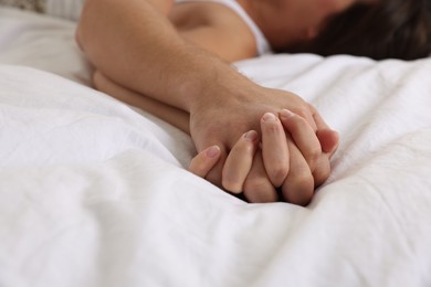 Lovely couple holding hands in bed, closeup