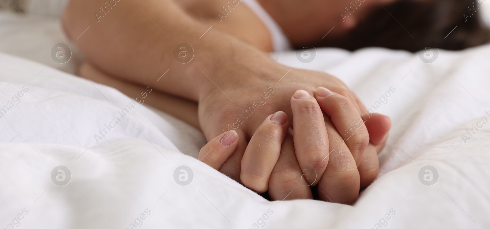 Photo of Lovely couple holding hands in bed, closeup