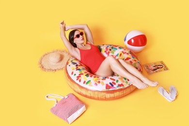 Photo of Beautiful woman in swimsuit with beach accessories on yellow background