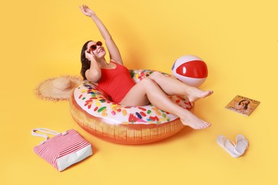 Photo of Beautiful woman in swimsuit with beach accessories on yellow background