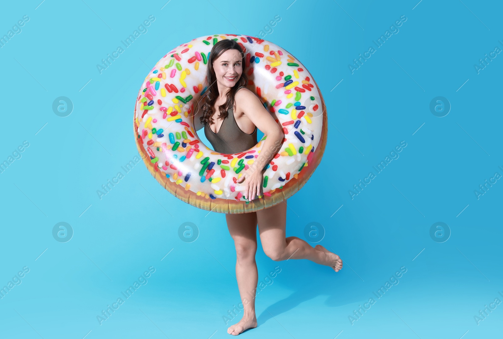 Photo of Beautiful woman in swimsuit with inflatable ring on light blue background