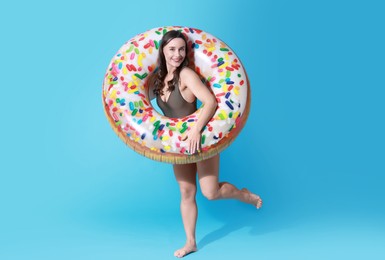 Photo of Beautiful woman in swimsuit with inflatable ring on light blue background