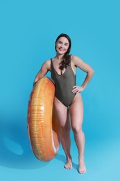 Photo of Beautiful woman in swimsuit with inflatable ring on light blue background