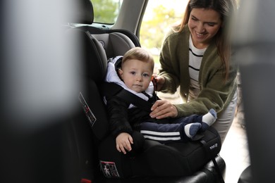 Photo of Smiling mother fastening her baby in car seat