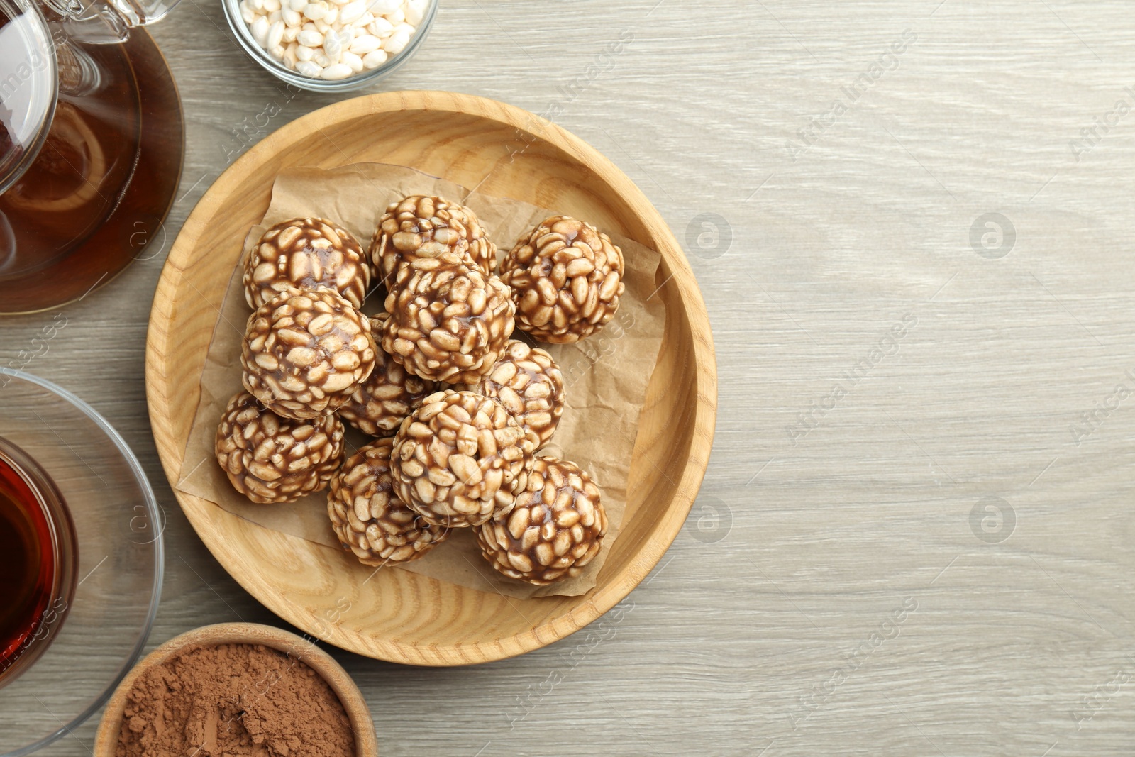 Photo of Tasty chocolate puffed rice balls served with tea on wooden table, flat lay. Space for text