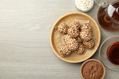 Photo of Tasty chocolate puffed rice balls served with tea on wooden table, flat lay. Space for text