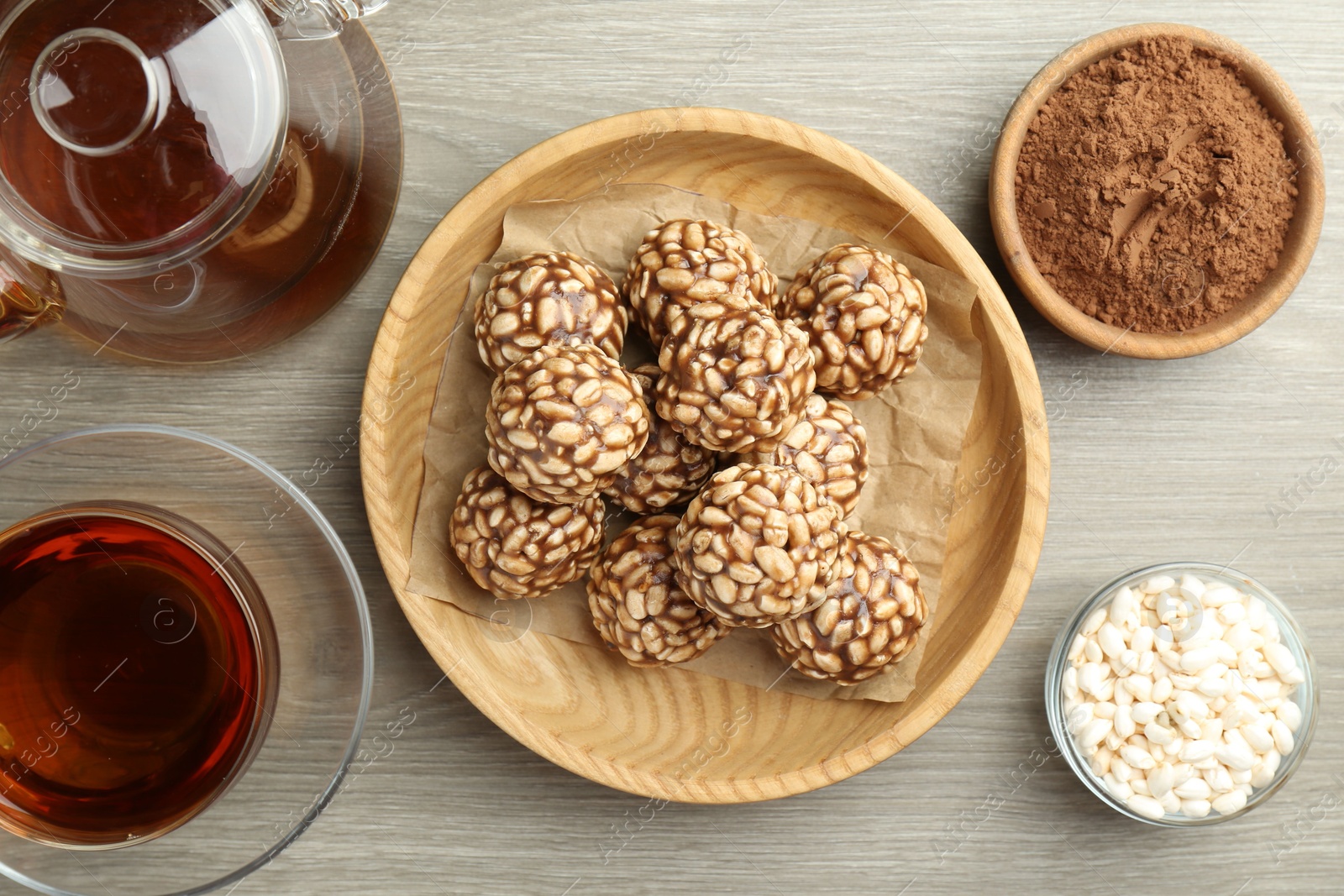 Photo of Tasty chocolate puffed rice balls served with tea on wooden table, flat lay