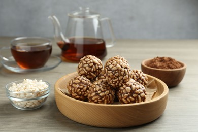 Photo of Tasty chocolate puffed rice balls served with tea on wooden table, closeup