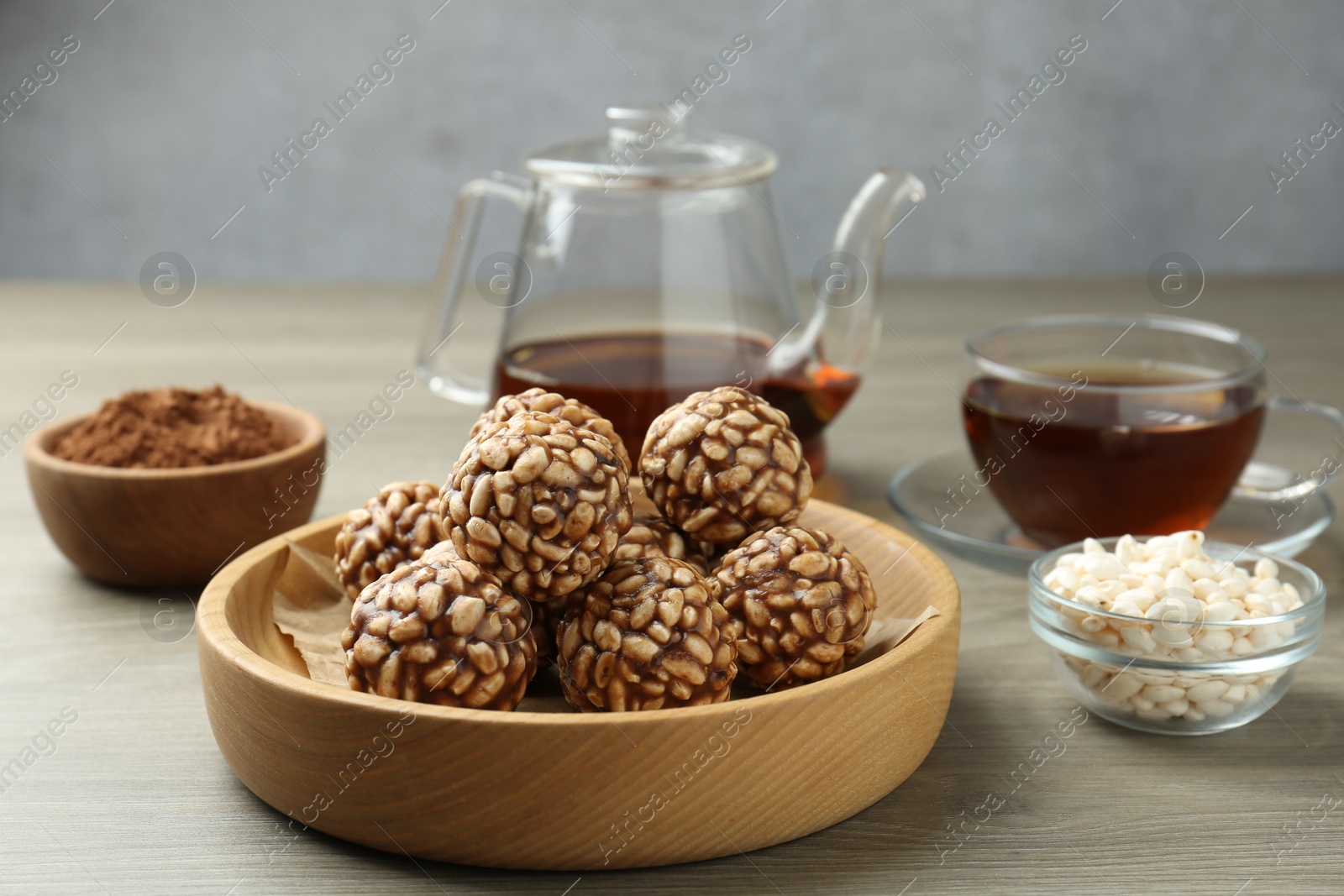 Photo of Tasty chocolate puffed rice balls served with tea on wooden table, closeup