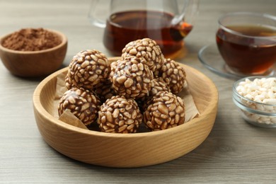 Photo of Tasty chocolate puffed rice balls served with tea on wooden table, closeup