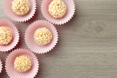 Tasty puffed rice balls on wooden table, flat lay. Space for text