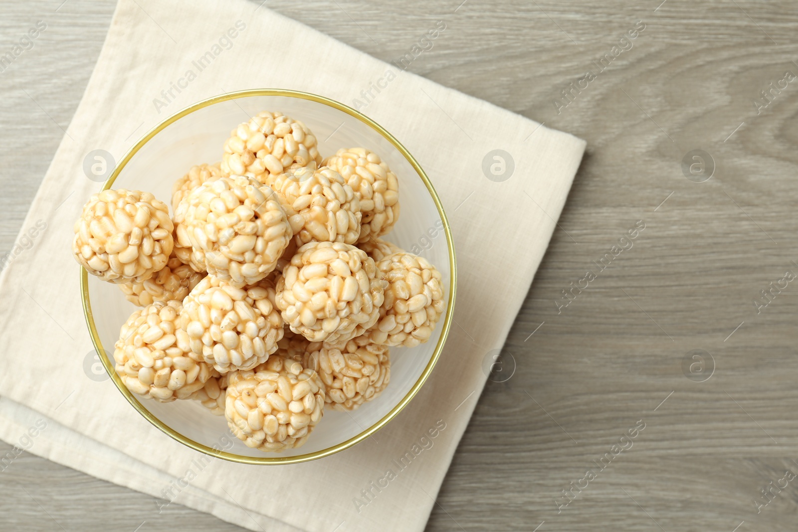 Photo of Tasty puffed rice balls in bowl on wooden table, top view. Space for text