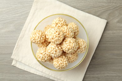 Tasty puffed rice balls in bowl on wooden table, top view