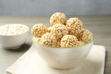 Photo of Tasty puffed rice balls in bowl on table, closeup