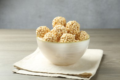 Photo of Tasty puffed rice balls in bowl on wooden table