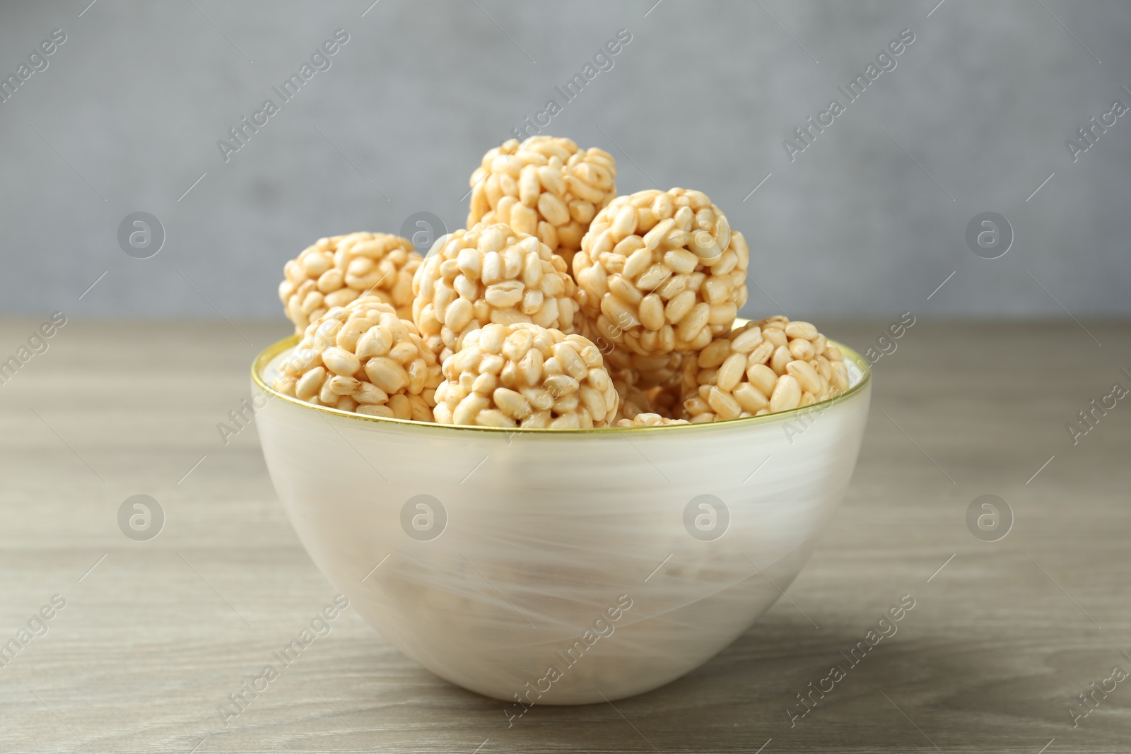 Photo of Tasty puffed rice balls in bowl on wooden table, closeup