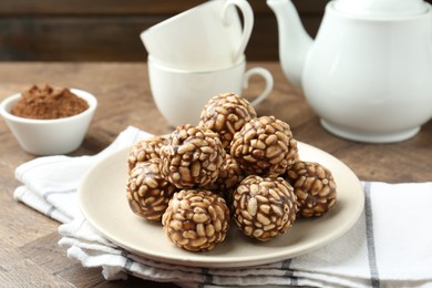 Tasty chocolate puffed rice balls served on wooden table, closeup