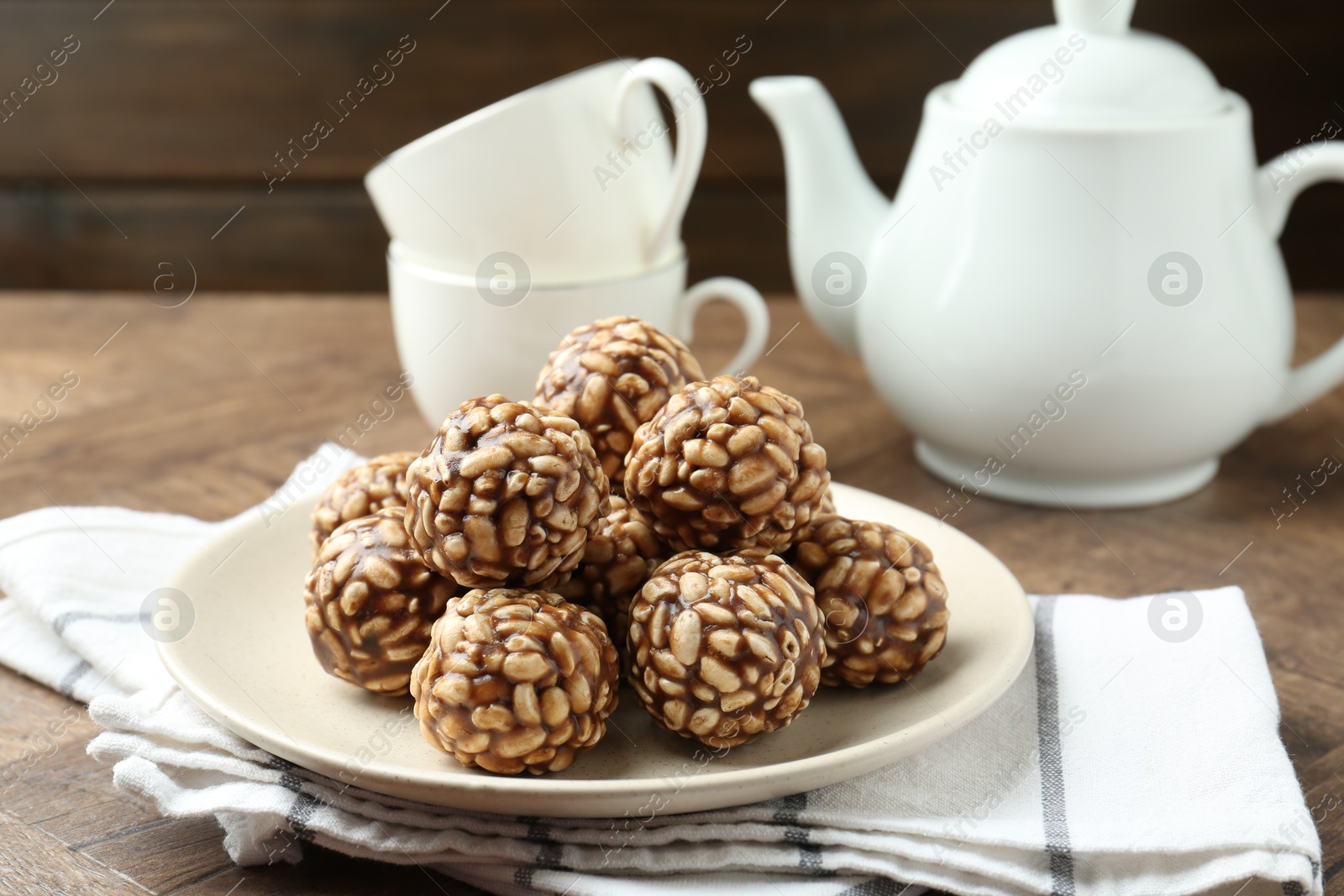 Photo of Tasty chocolate puffed rice balls served on wooden table, closeup