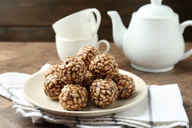 Tasty chocolate puffed rice balls served on wooden table, closeup