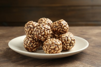 Tasty chocolate puffed rice balls on wooden table, closeup