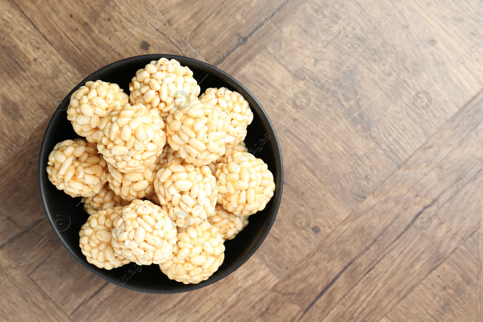 Photo of Tasty puffed rice balls on wooden table, top view. Space for text