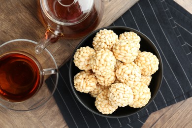 Tasty puffed rice balls and tea on wooden table, flat lay