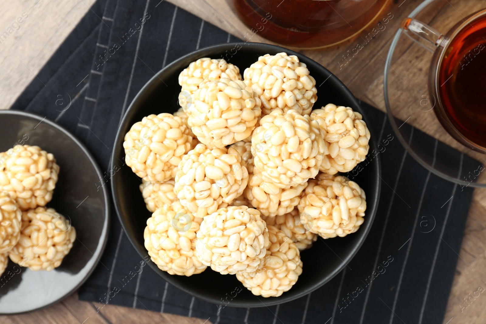 Photo of Tasty puffed rice balls and tea on wooden table, flat lay