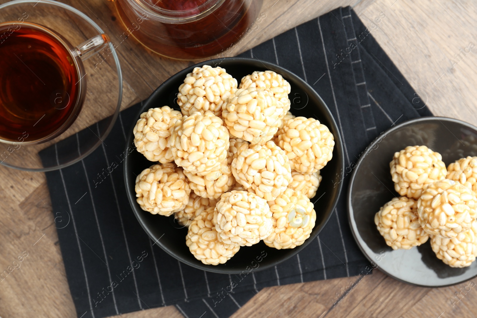 Photo of Tasty puffed rice balls and tea on wooden table, flat lay