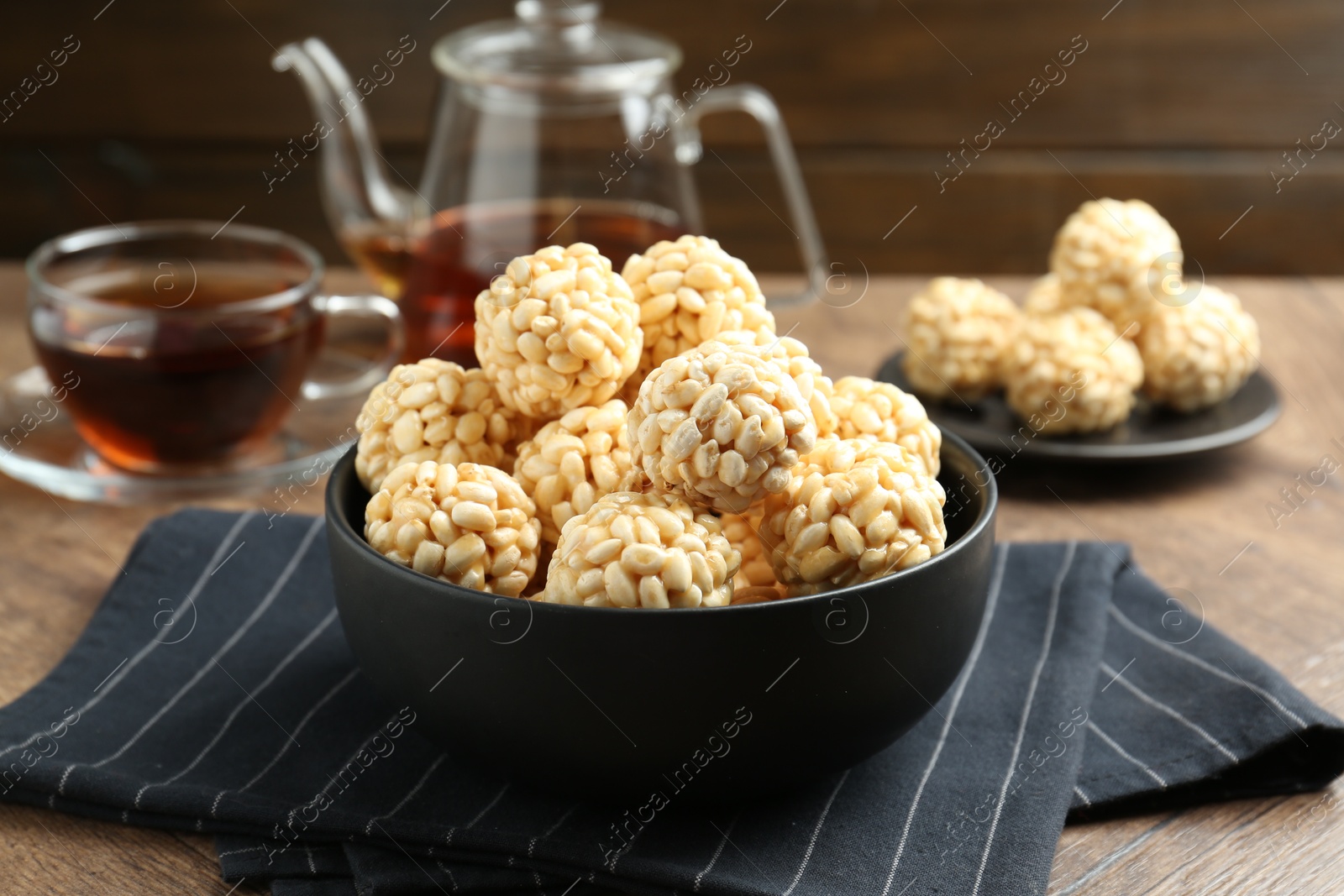 Photo of Tasty puffed rice balls in bowl on wooden table, closeup