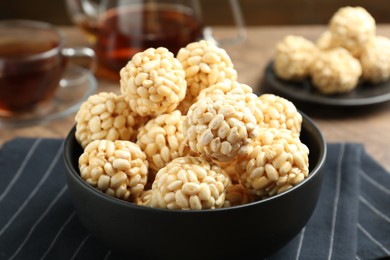 Photo of Tasty puffed rice balls in bowl on table, closeup