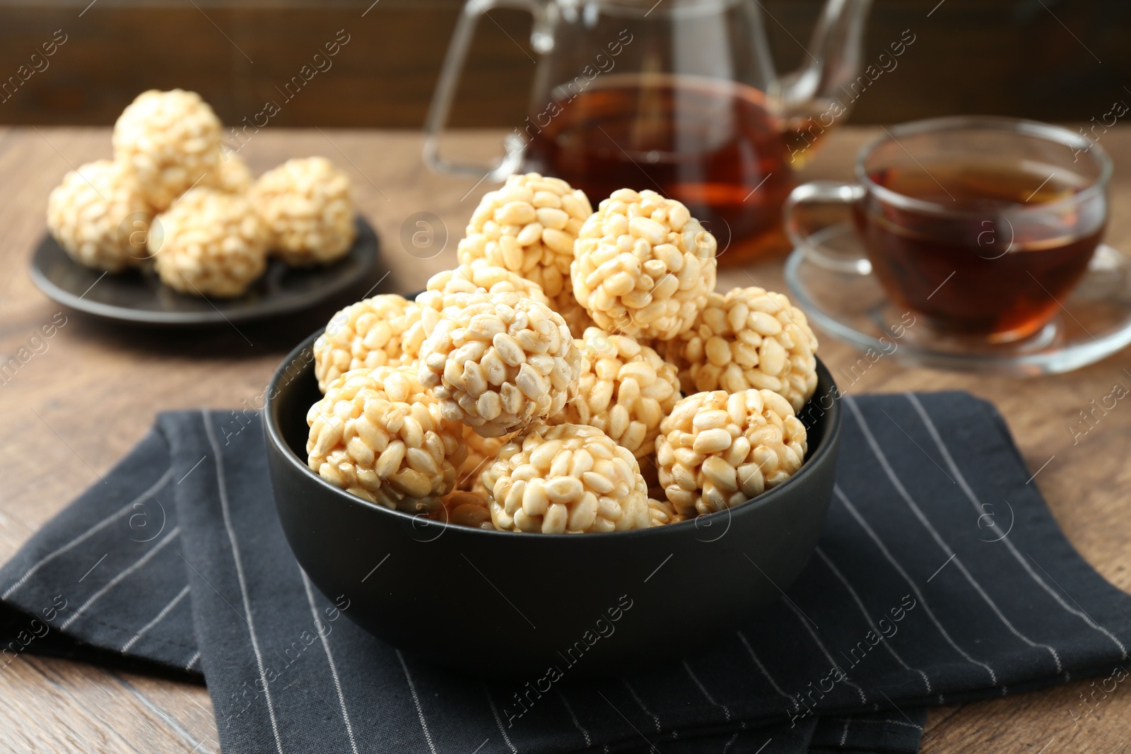 Photo of Tasty puffed rice balls in bowl on wooden table, closeup