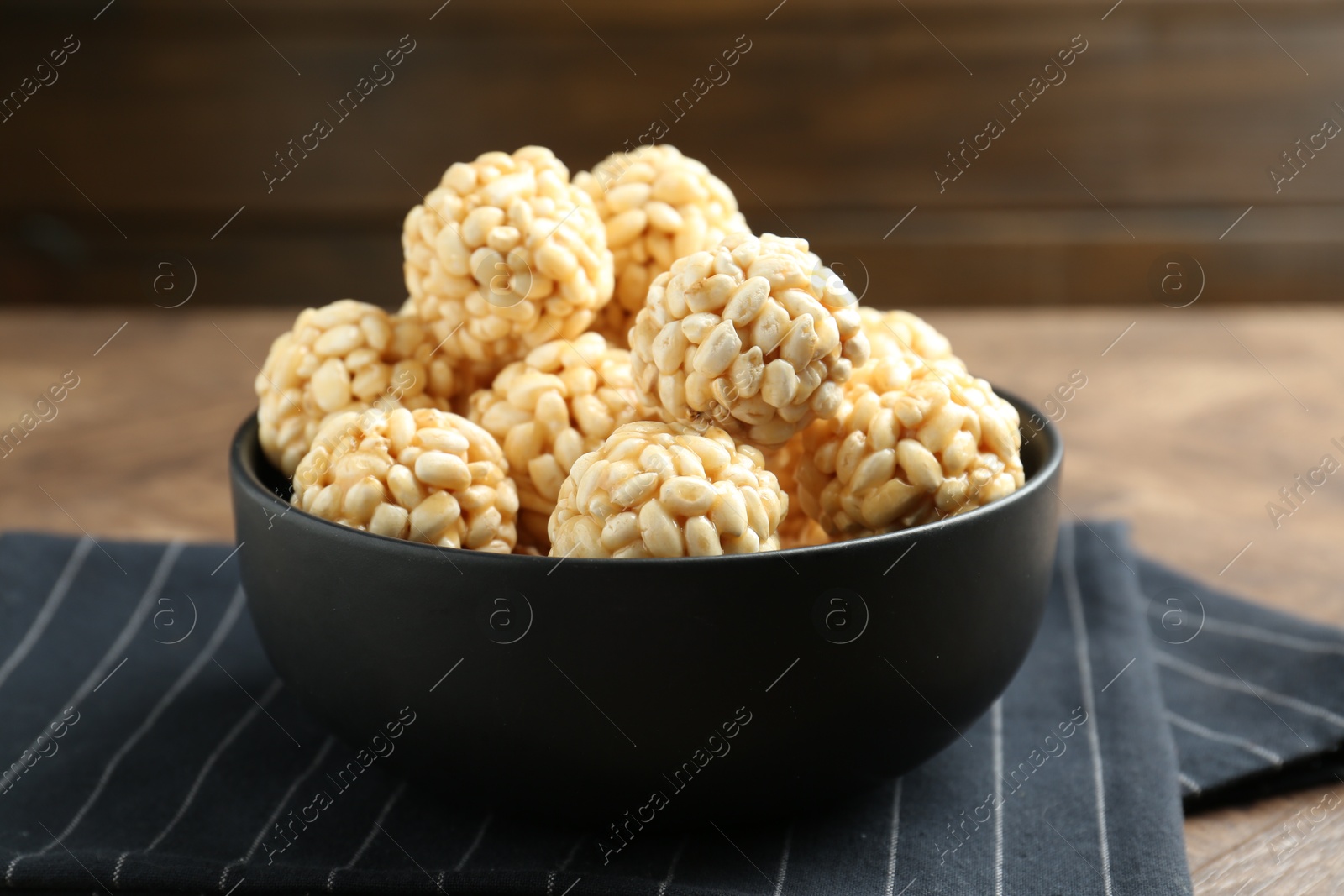 Photo of Tasty puffed rice balls in bowl on table, closeup