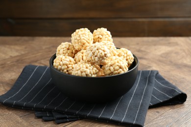 Photo of Tasty puffed rice balls in bowl on wooden table