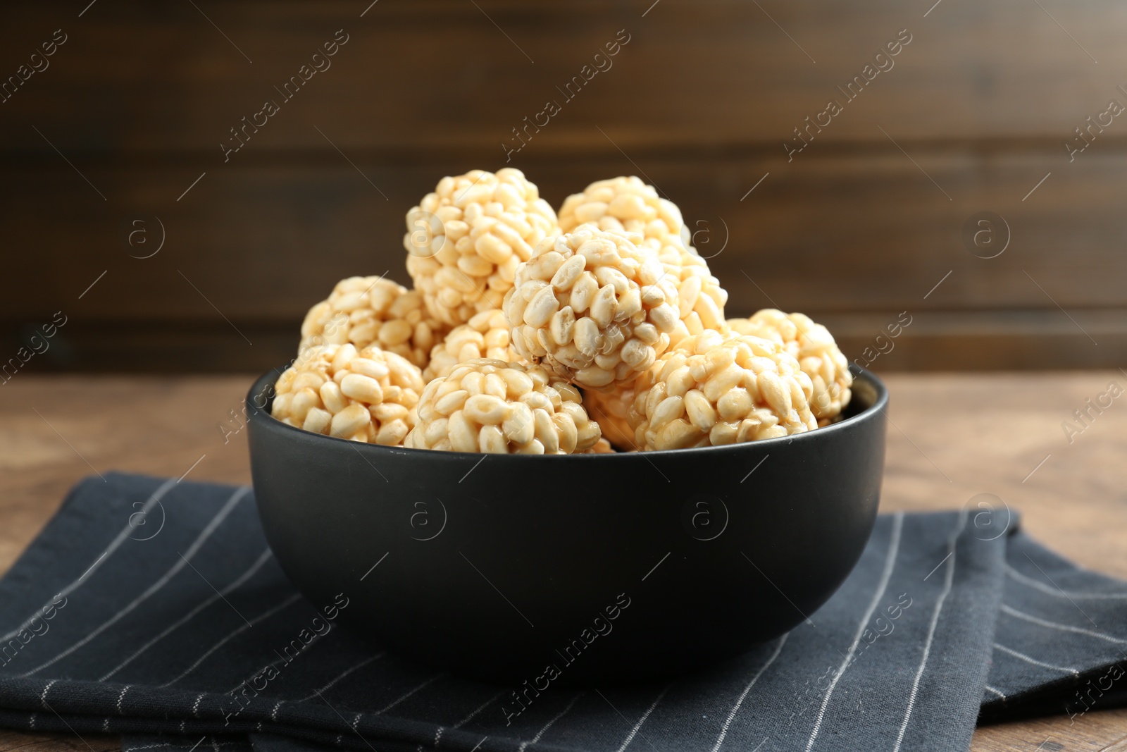 Photo of Tasty puffed rice balls in bowl on table, closeup