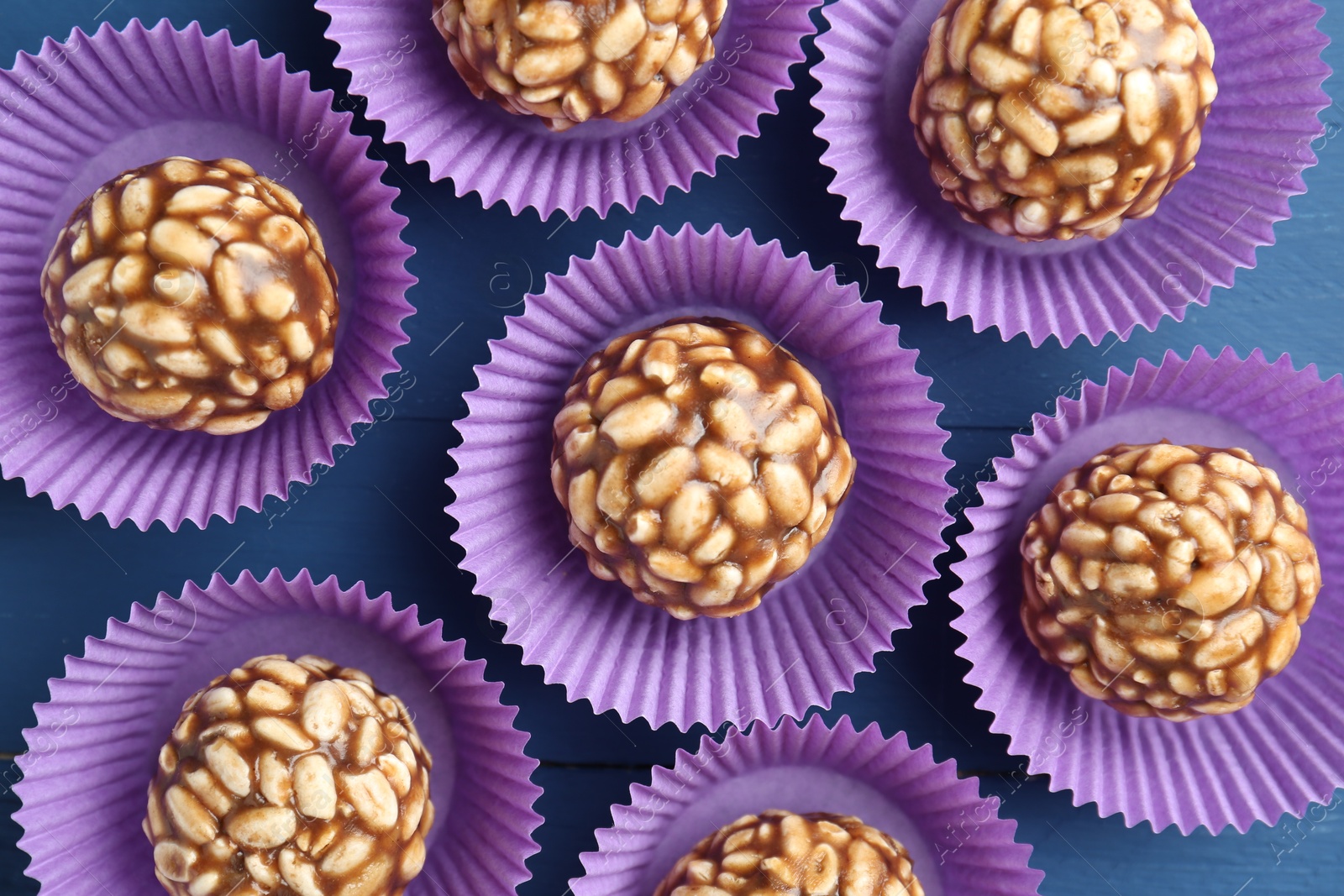 Photo of Tasty chocolate puffed rice balls on blue wooden table, flat lay