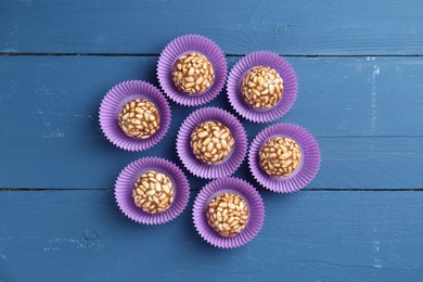 Tasty chocolate puffed rice balls on blue wooden table, flat lay