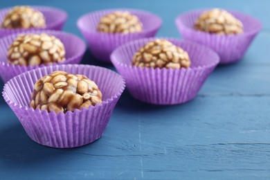 Photo of Tasty chocolate puffed rice balls on blue wooden table, closeup. Space for text