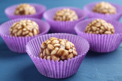 Photo of Tasty chocolate puffed rice balls on blue wooden table, closeup