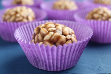 Tasty chocolate puffed rice balls on blue wooden table, closeup