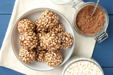 Tasty chocolate puffed rice balls and ingredients on blue wooden table, flat lay