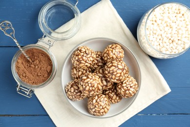 Tasty chocolate puffed rice balls and ingredients on blue wooden table, flat lay