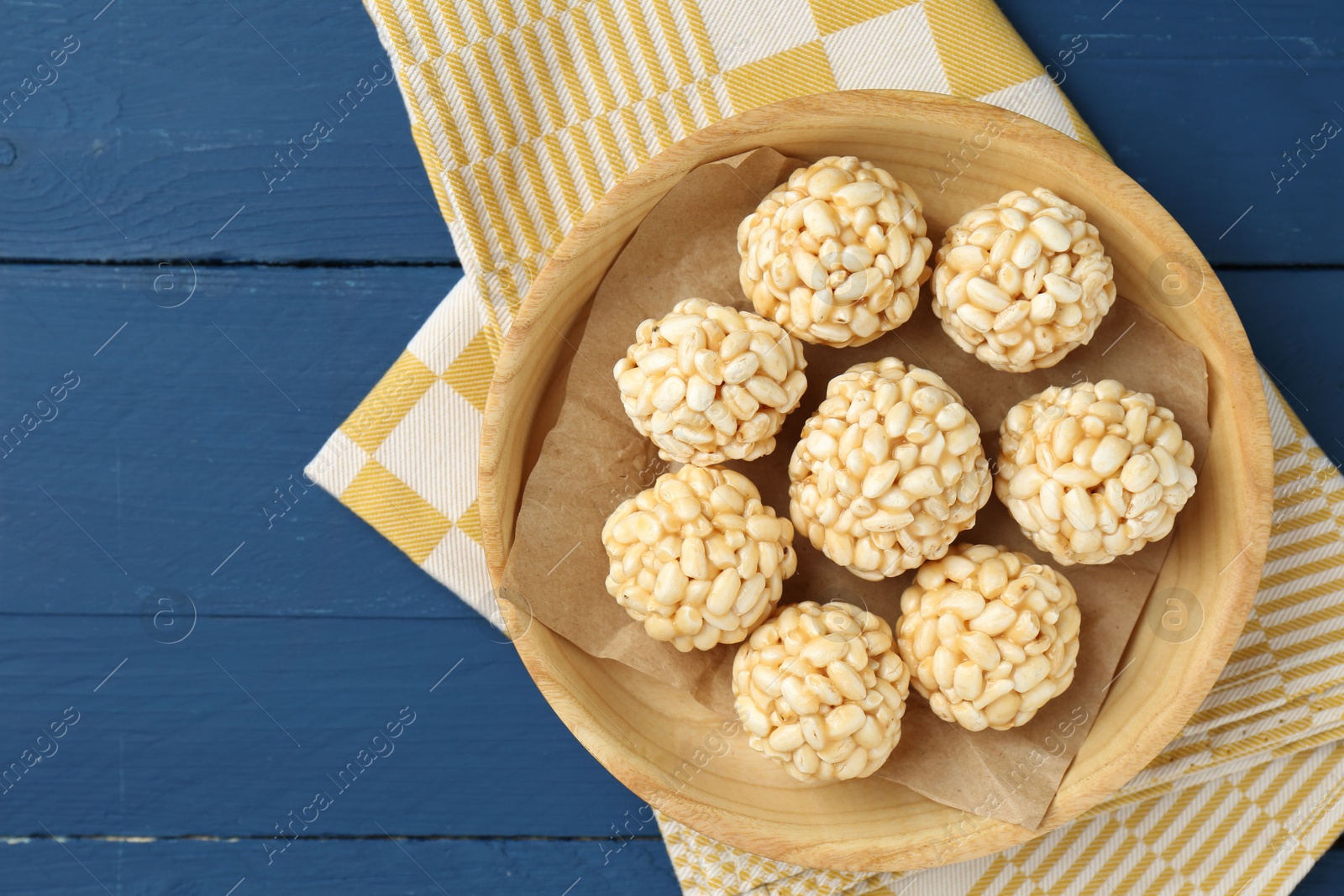 Photo of Tasty puffed rice balls on blue wooden table, top view. Space for text