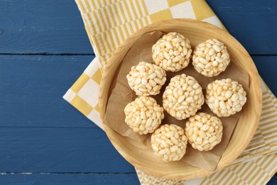 Photo of Tasty puffed rice balls on blue wooden table, top view. Space for text