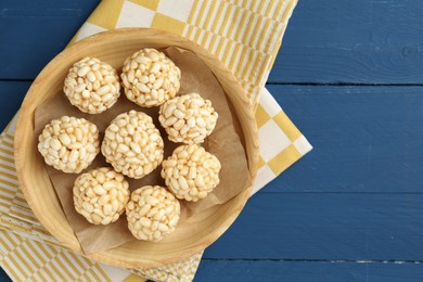 Tasty puffed rice balls on blue wooden table, top view. Space for text