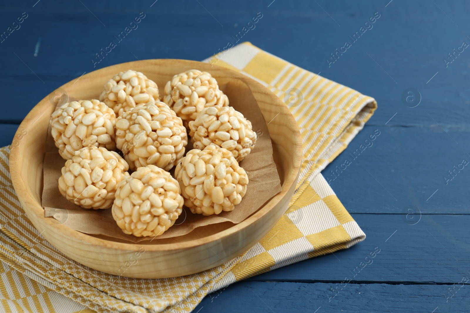 Photo of Tasty puffed rice balls on blue wooden table, closeup. Space for text