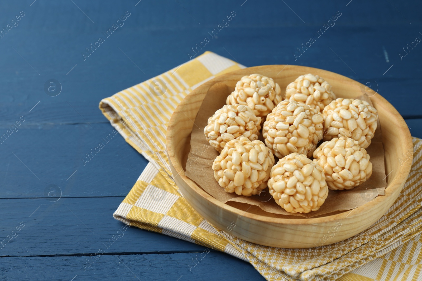 Photo of Tasty puffed rice balls on blue wooden table, closeup. Space for text